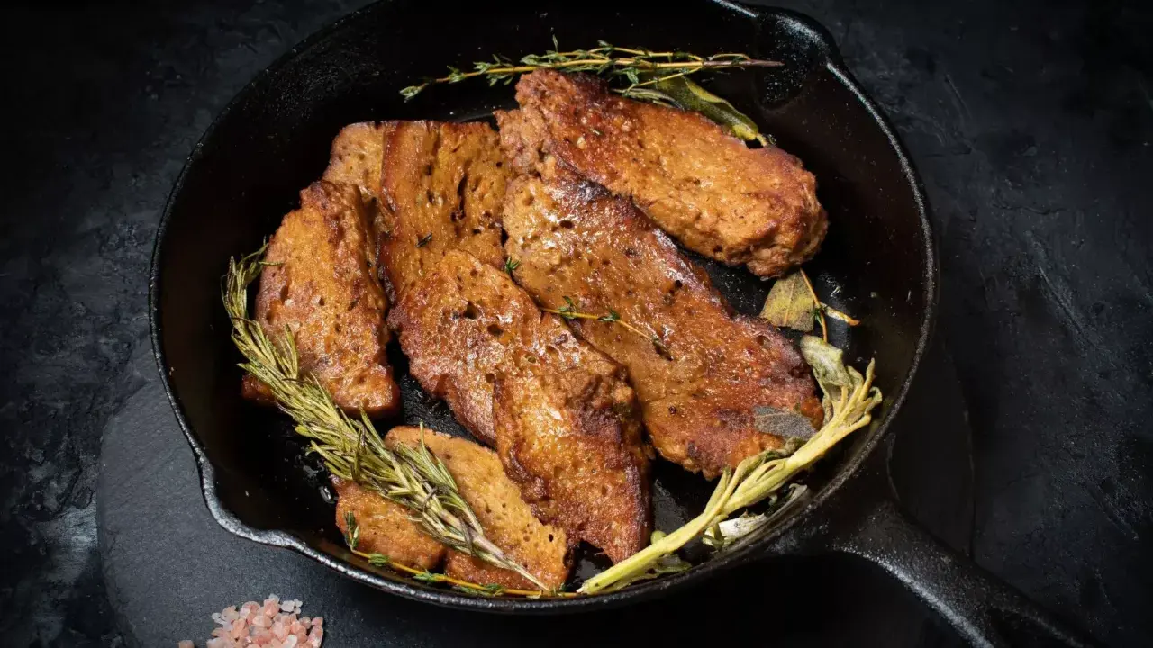 Seitan que es: trozos dorados y sabrosos de seitan cocinados en sartén con hierbas aromáticas como romero y tomillo.