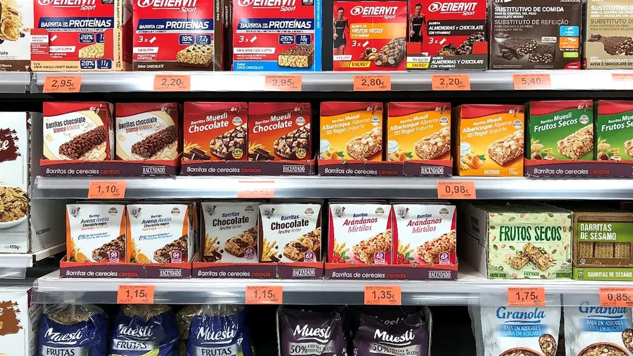 Estanterías de Mercadona con barritas proteicas y de cereales. Variedad de sabores y marcas, con información sobre su valor nutricional.