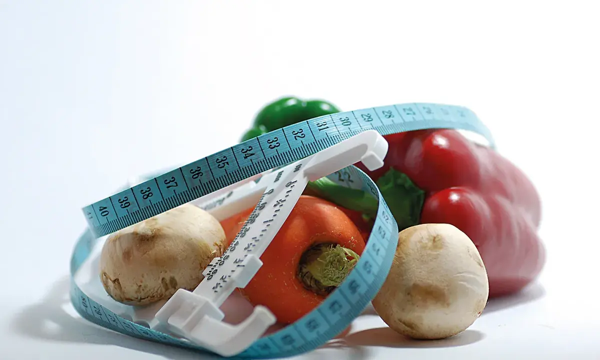 Verduras frescas y cinta métrica, símbolos de dietas milagro y un estilo de vida saludable.