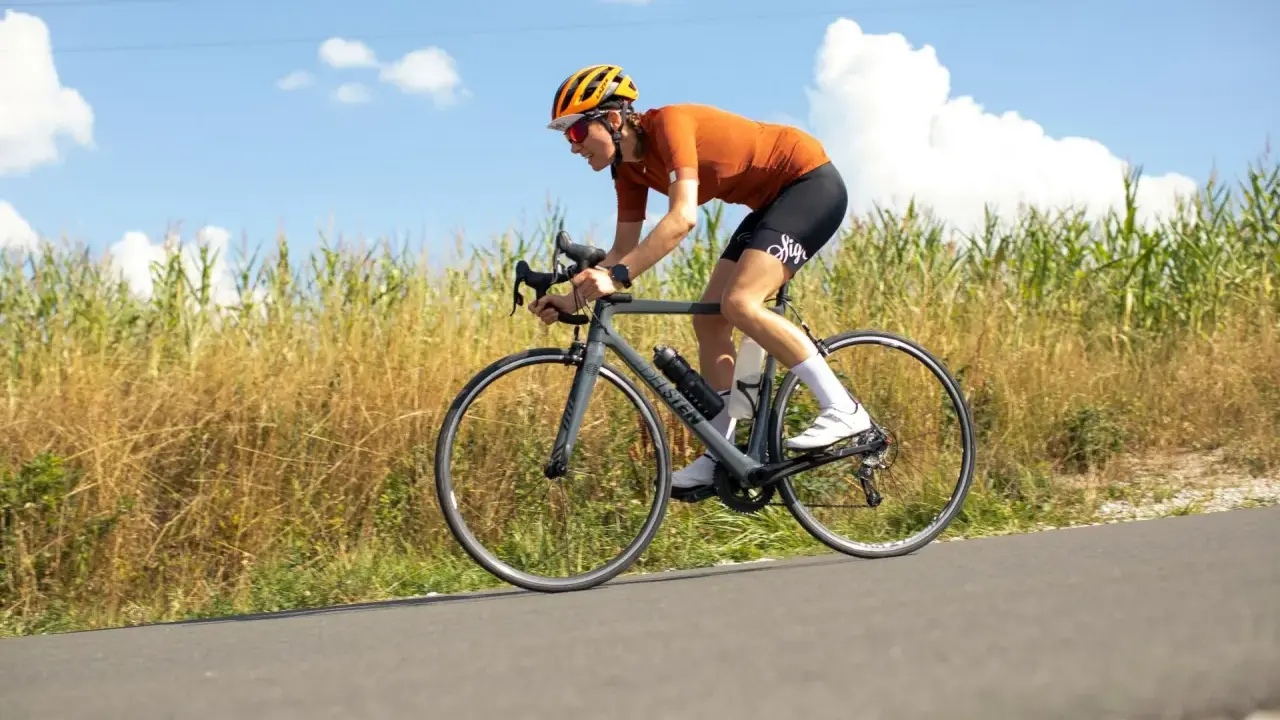 Ciclista en ruta, con casco y gafas, pedaleando con energía. En su bidón lleva lo que toman los ciclistas para recuperar.
