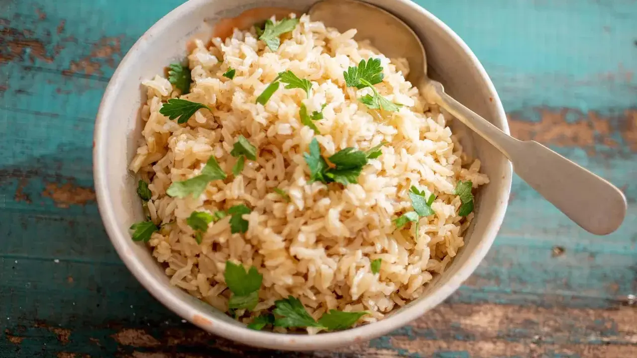 Un tazón de arroz integral esponjoso, adornado con perejil fresco, listo para ser disfrutado.