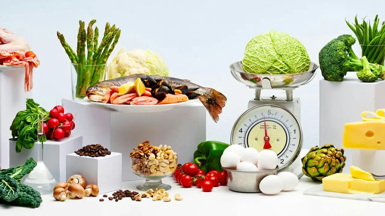 Variedad de alimentos bajos en carbohidratos: pescado, mariscos, verduras, huevos, frutos secos y queso.
