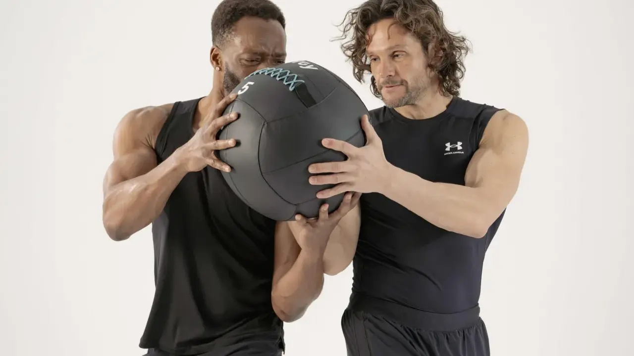 Dos hombres preparándose para el lanzamiento de un balón medicinal.