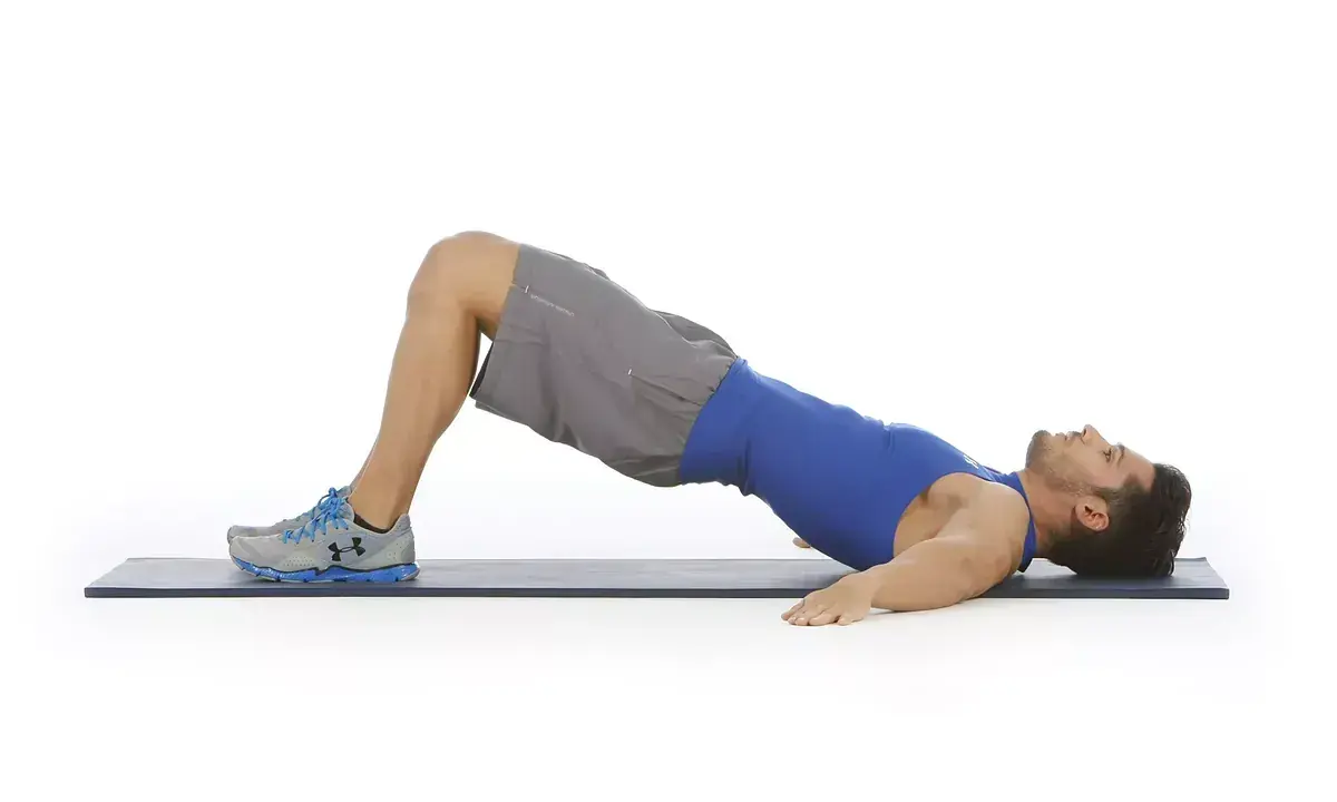 Hombre haciendo puente de glúteo, ejercicio para la extensión lumbar.