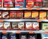 Estanterías de Mercadona con barritas proteicas y de cereales. Variedad de sabores y marcas, con información sobre su valor nutricional.