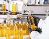 Manos enguantadas revisan botellas de líquido dorado, quizás para advertir que el aceite de girasol es malo.