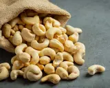 Anacardos desbordándose de un saco de arpillera, mostrando sus deliciosas propiedades nutritivas.
