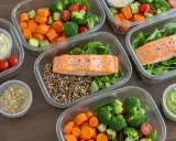 Preparación de comidas saludables: salmón, quinoa, brócoli, zanahorias y aderezos para un menú sin carbohidratos.