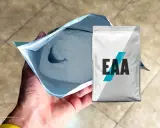 Un paquete abierto de polvo blanco, con un paquete de EAA al lado. ¿EAA para qué sirve? Para la recuperación muscular.