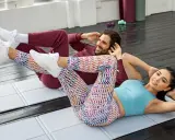 Pareja haciendo plancha con elevación de pierna en colchonetas.
