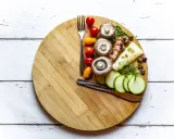 Tabla de cortar con ingredientes saludables: champiñones, tomates, calabacín, queso y aceitunas. Ideas para saber qué comer para romper el ayuno intermitente 16/8.
