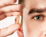 Un hombre sostiene una cápsula de aceite de pescado, destacando los omega 3 beneficios para hombres.
