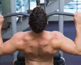 Hombre entrenando espalda con polea agarre cerrado. Músculos definidos trabajando en el gimnasio.
