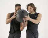 Dos hombres preparándose para el lanzamiento de un balón medicinal.