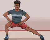 Hombre realizando una apertura lateral de piernas, con las manos en las caderas, estirando sus músculos.
