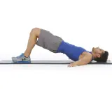 Hombre haciendo puente de glúteo, ejercicio para la extensión lumbar.