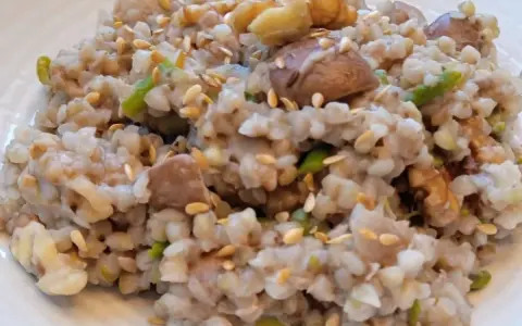 Un plato de trigo sarraceno cocido con trozos de nuez y semillas de sésamo esparcidas.