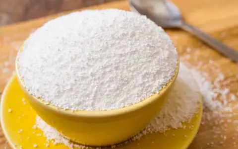 Tazón amarillo lleno de polvo blanco, posiblemente sorbitol. Cuidado con los alimentos prohibidos que lo contienen.