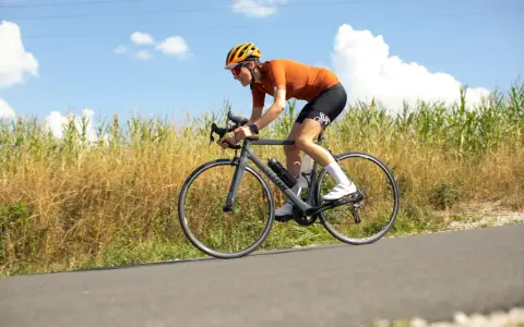 Ciclista en ruta, con casco y gafas, pedaleando con energía. En su bidón lleva lo que toman los ciclistas para recuperar.