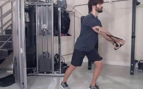 Hombre realizando ejercicio de cruce poleas en gimnasio.
