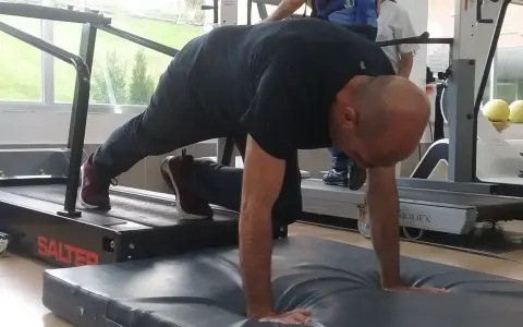 Hombre realizando ejercicio de cuadrupedia en una cinta de correr, con manos apoyadas en colchoneta.