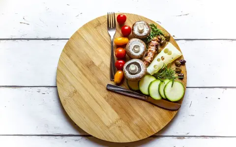 Tabla de cortar con ingredientes saludables: champiñones, tomates, calabacín, queso y aceitunas. Ideas para saber qué comer para romper el ayuno intermitente 16/8.