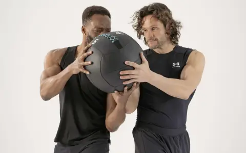 Dos hombres preparándose para el lanzamiento de un balón medicinal.