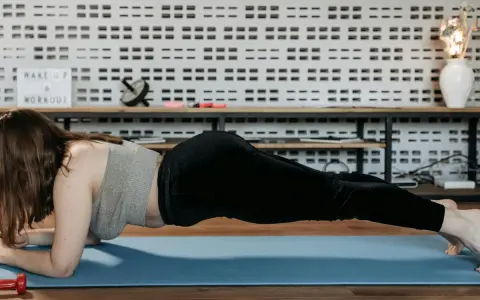 Mujer realizando ejercicio de **plancha antebrazos** en una esterilla azul.