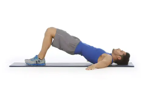 Hombre haciendo puente de glúteo, ejercicio para la extensión lumbar.