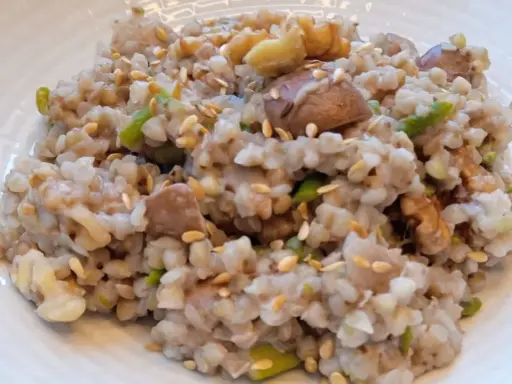 Un plato de trigo sarraceno cocido con trozos de nuez y semillas de sésamo esparcidas.