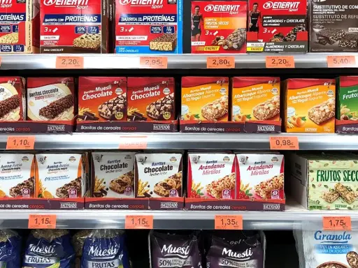 Estanterías de Mercadona con barritas proteicas y de cereales. Variedad de sabores y marcas, con información sobre su valor nutricional.