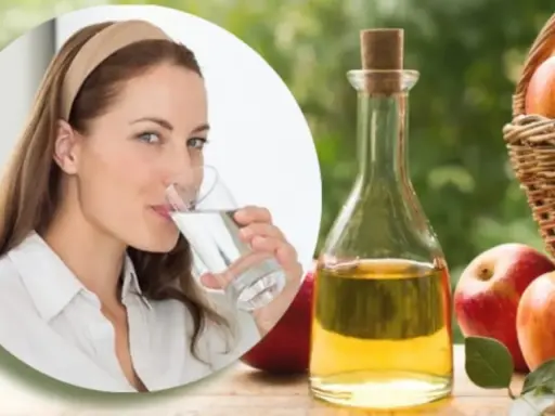 Mujer bebe agua, junto a botella de vinagre de manzana y manzanas. Una rutina saludable para tomar vinagre de manzana en ayunas.
