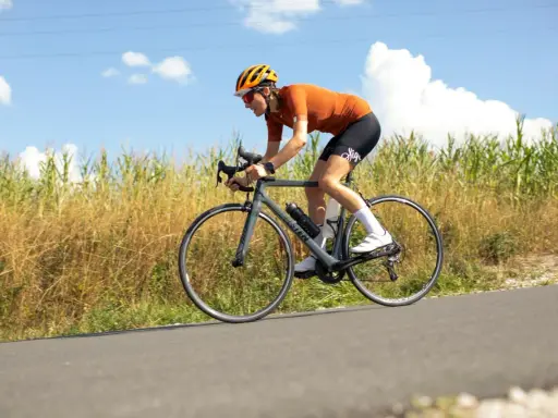 Ciclista en ruta, con casco y gafas, pedaleando con energía. En su bidón lleva lo que toman los ciclistas para recuperar.