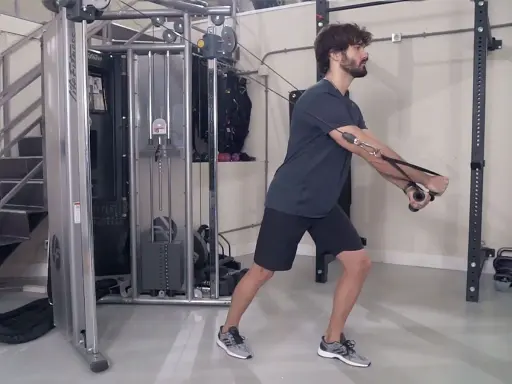 Hombre realizando ejercicio de cruce poleas en gimnasio.