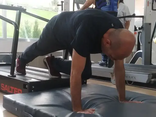 Hombre realizando ejercicio de cuadrupedia en una cinta de correr, con manos apoyadas en colchoneta.