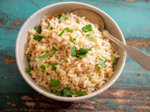 Un tazón de arroz integral esponjoso, adornado con perejil fresco, listo para ser disfrutado.
