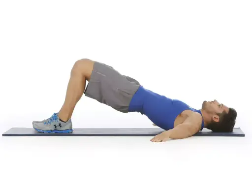 Hombre haciendo puente de glúteo, ejercicio para la extensión lumbar.