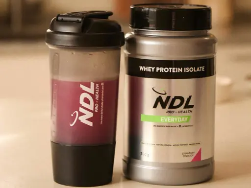 Batido de proteína NDL y su envase. ¿Cuántos scoops de proteína tomar? Elige tu sabor favorito.