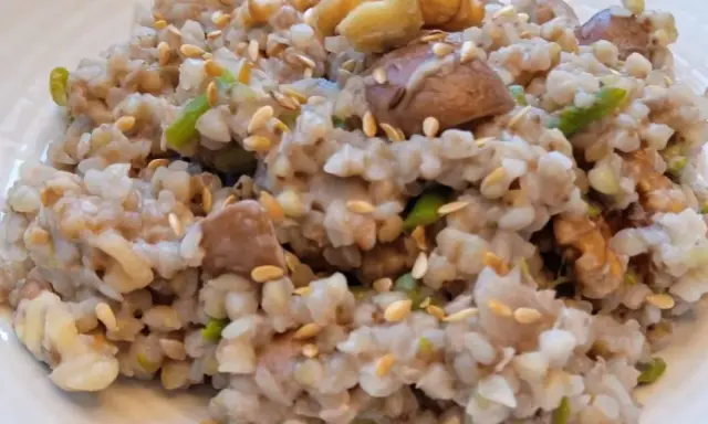 Un plato de trigo sarraceno cocido con trozos de nuez y semillas de sésamo esparcidas.