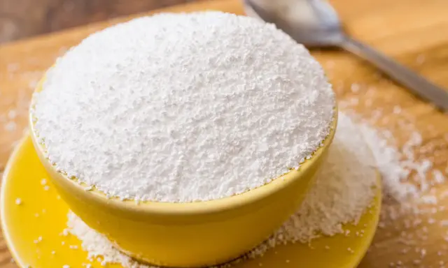 Tazón amarillo lleno de polvo blanco, posiblemente sorbitol. Cuidado con los alimentos prohibidos que lo contienen.