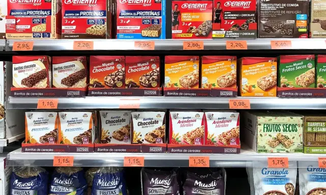 Estanterías de Mercadona con barritas proteicas y de cereales. Variedad de sabores y marcas, con información sobre su valor nutricional.