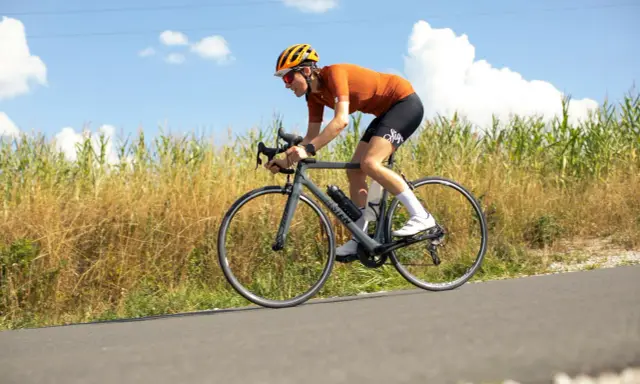 Ciclista en ruta, con casco y gafas, pedaleando con energía. En su bidón lleva lo que toman los ciclistas para recuperar.