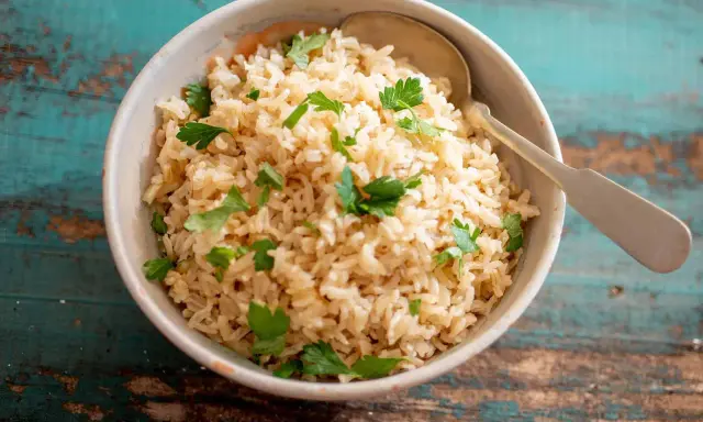 Un tazón de arroz integral esponjoso, adornado con perejil fresco, listo para ser disfrutado.