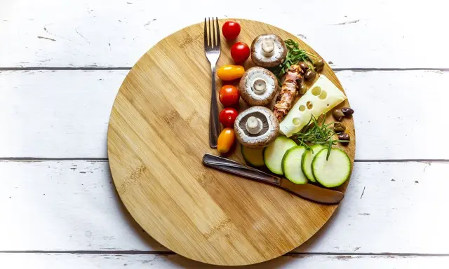 Tabla de cortar con ingredientes saludables: champiñones, tomates, calabacín, queso y aceitunas. Ideas para saber qué comer para romper el ayuno intermitente 16/8.