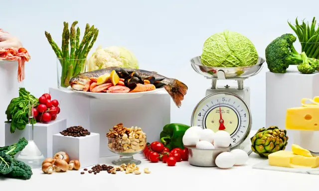 Variedad de alimentos bajos en carbohidratos: pescado, mariscos, verduras, huevos, frutos secos y queso.