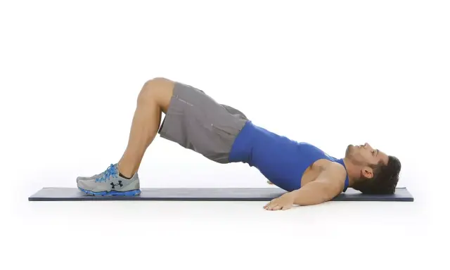 Hombre haciendo puente de glúteo, ejercicio para la extensión lumbar.