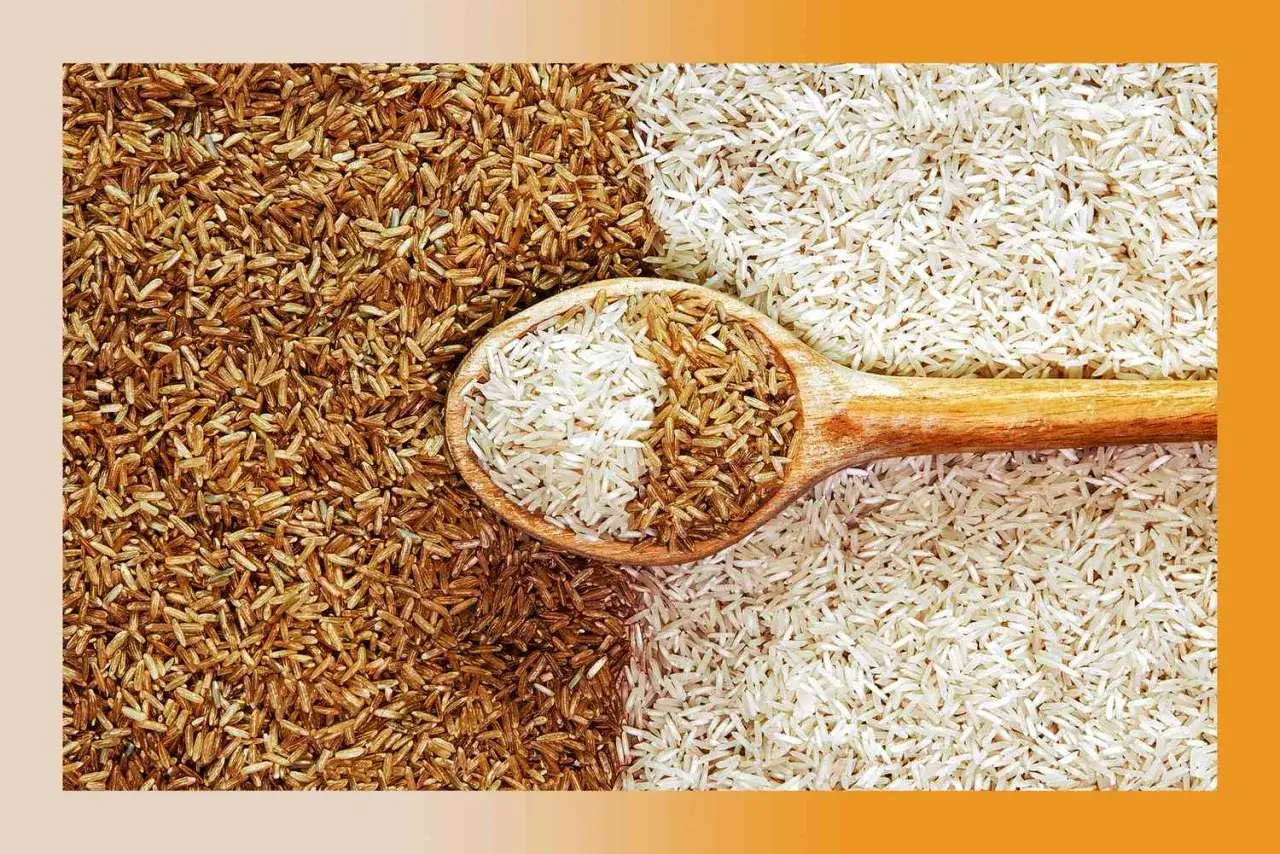 Una cuchara de madera contiene arroz integral y blanco, sobre un lecho de ambos.