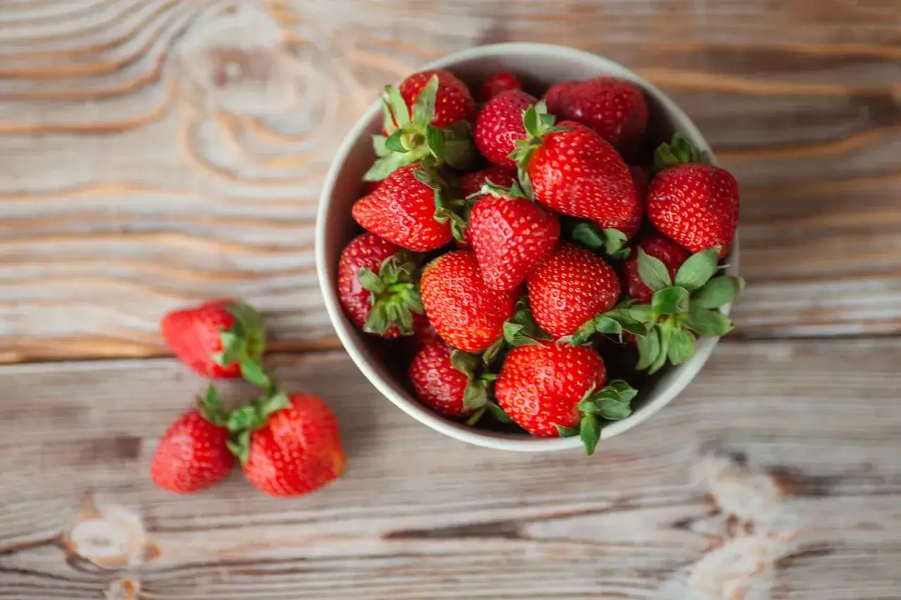 Un tazón lleno de fresas rojas y jugosas, perfectas para un snack saludable con pocas calorías.