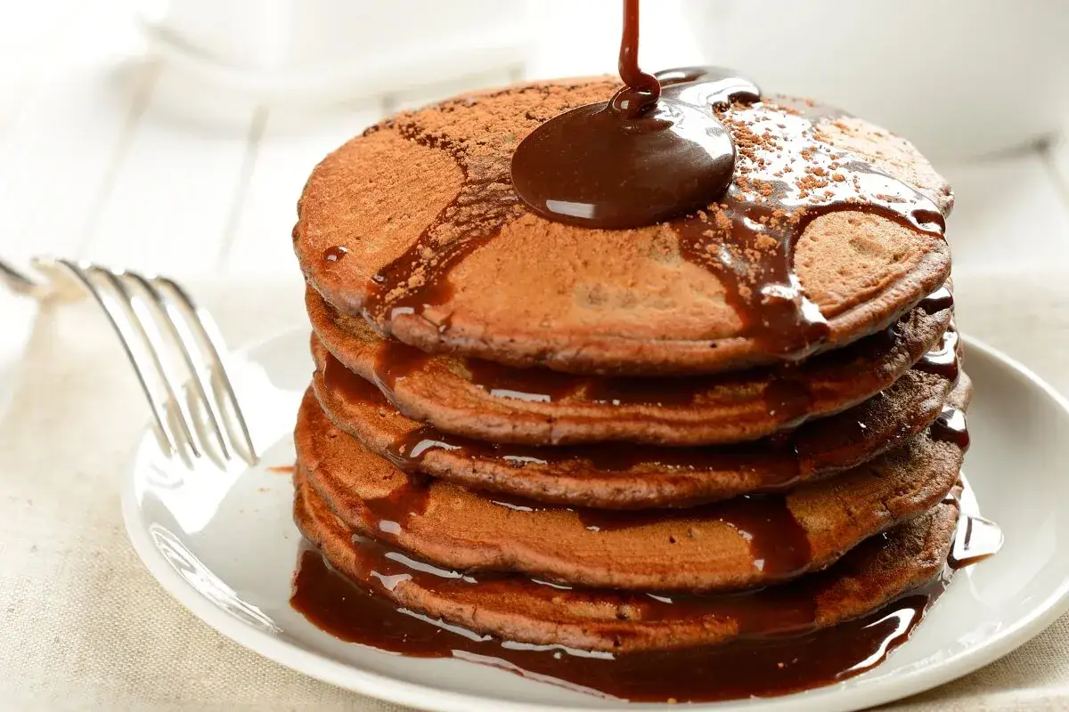 Pila de tortitas de cacao puro, cubiertas con sirope de chocolate. Disfruta de los beneficios del cacao puro en cada bocado.
