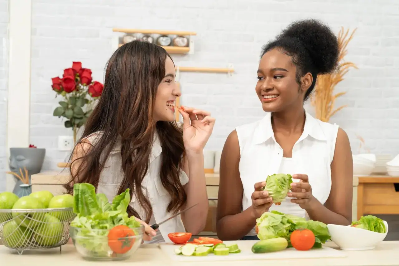 Dos adolescentes preparan una ensalada, un snack saludable con omega 3 para adolescentes.